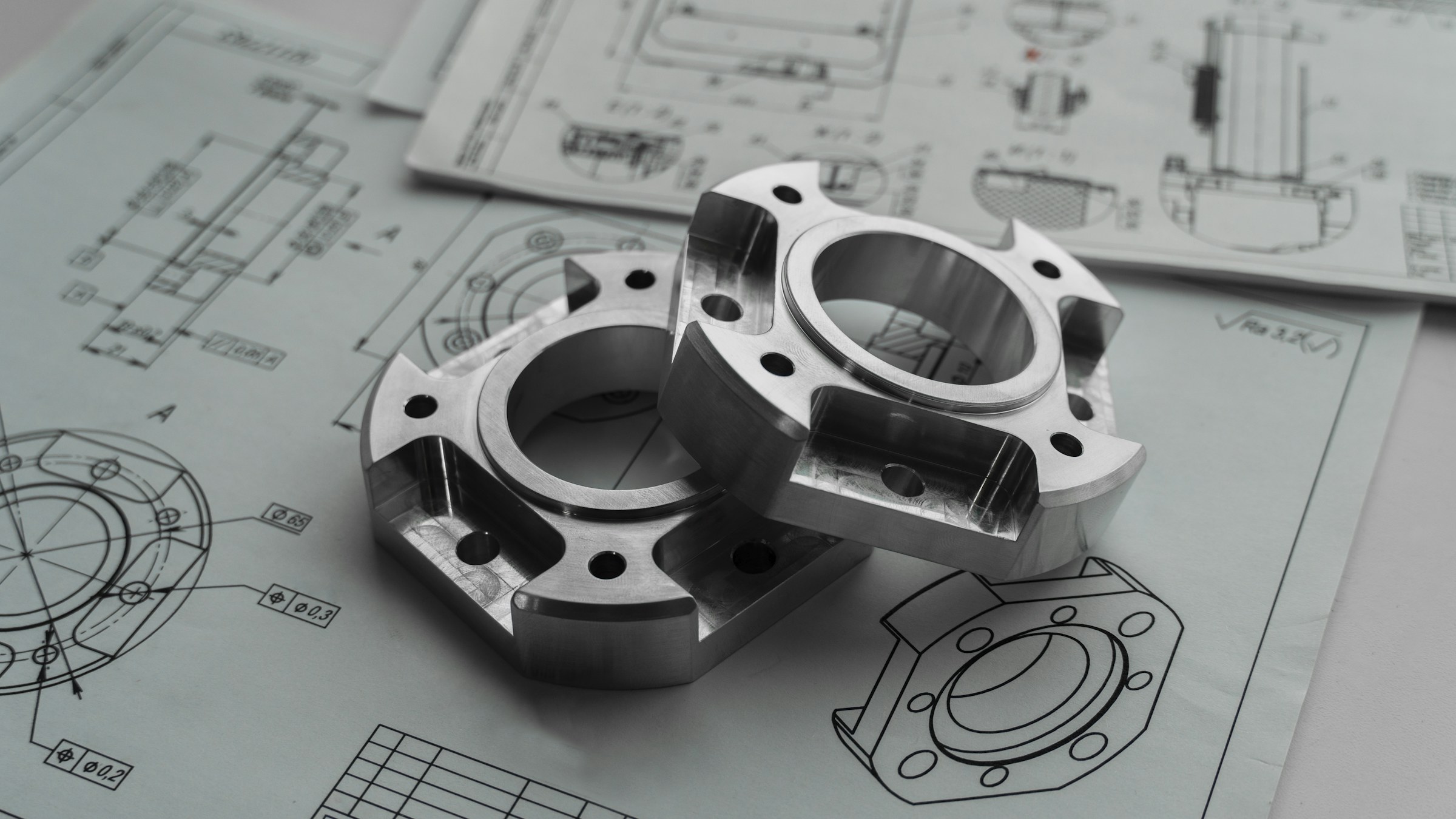 Planos de ingeniería con componentes metálicos sobre una mesa de trabajo